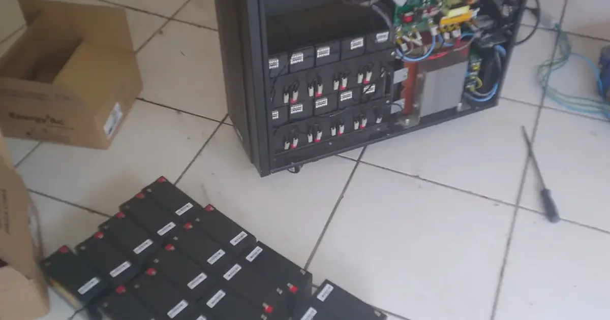 Banco de baterias retirado de um nobreak durante a troca, ao lado do equipamento aberto com o compartimento de baterias à mostra
